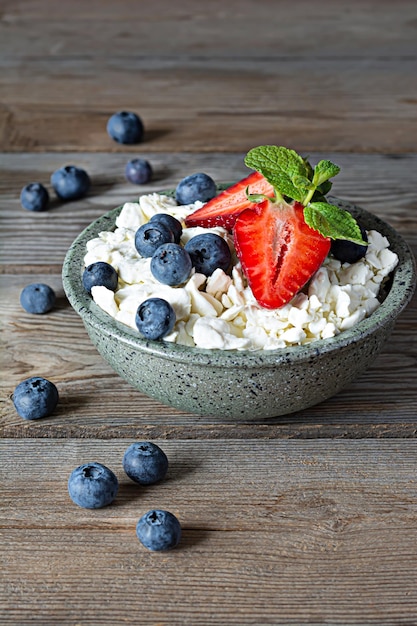 Un tazón con yogur de requesón, bayas frescas, arándanos, fresas y menta fresca