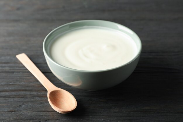 Tazón de yogurt de crema agria y cuchara sobre fondo de madera