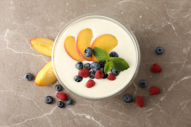 Tazón con yogurt de crema agria y frutas sobre fondo gris