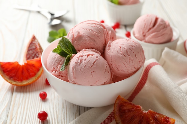 Tazones con bolas de helado en la mesa de madera blanca, de cerca