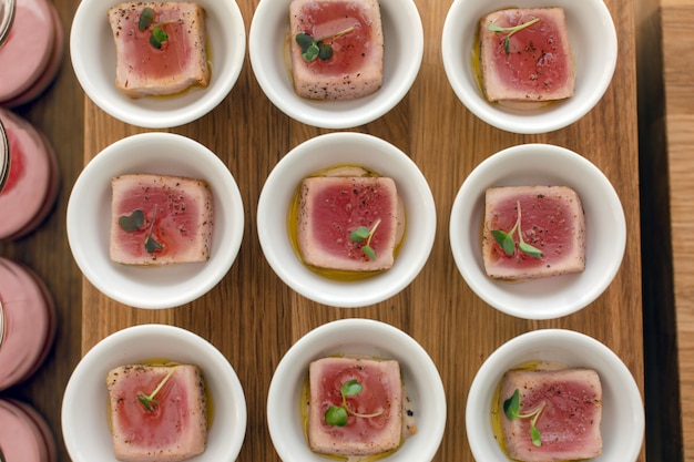 Tazones con deliciosos filetes de sintonía sobre tabla de madera