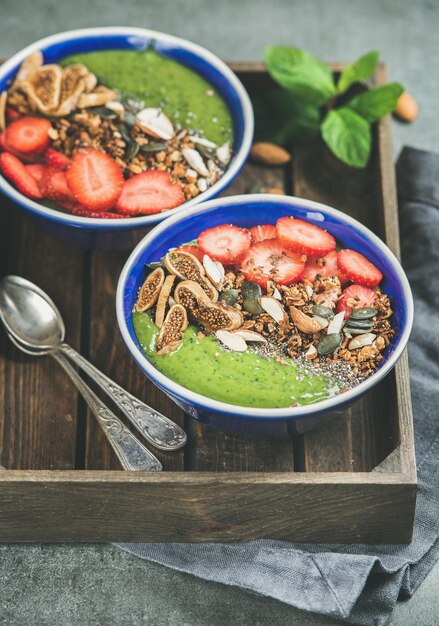 Tazones de desayuno de batido verde con semillas, nueces, frutas y bayas