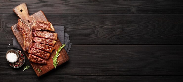 Tbone bife de carne grelhada com especiarias e ervas em amplo fundo de madeira Vista superior plana com espaço de cópia