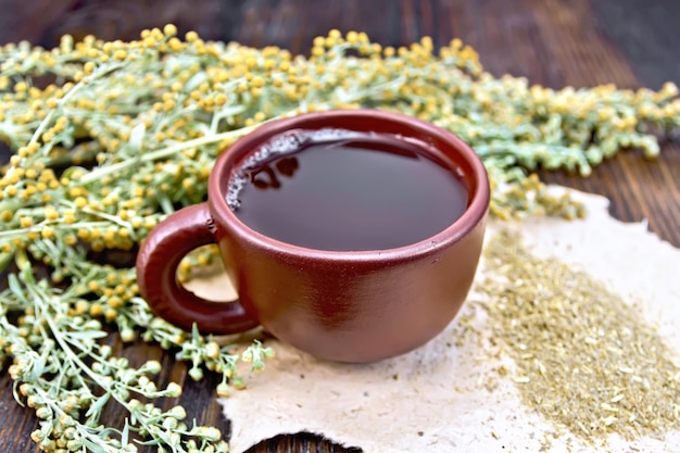 Té con ajenjo en taza marrón a bordo