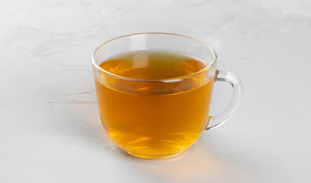 Té amarillo en una taza de vidrio transparente