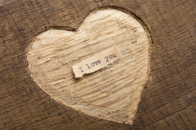 Foto te amo pequeña nota de texto escrita cerca del concepto de saludos del día de san valentín forma de corazón tallada en madera como fondo para la tarjeta de felicitación de san valentín