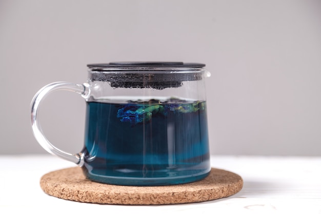 Foto té del azul de la flor del guisante de mariposa. bebida de hierbas de desintoxicación saludable. té de guisante de mariposa en tetera transparente en mesa de madera blanca