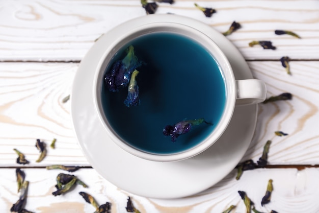 Foto té azul de la flor del guisante de mariposa en una taza blanca. bebida de hierbas de desintoxicación saludable. mariposa guisantes té azul anchan en una vista superior de la taza