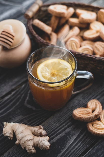 Té de bebida caliente con limón, miel y jengibre con galletas de jengibre sobre fondo de madera