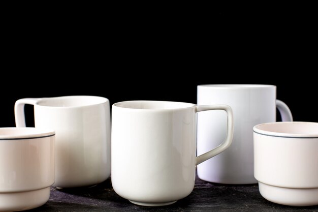 Té blanco y tazas de café de varias formas sobre una mesa de madera