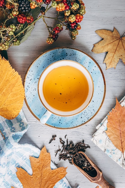 Té de calentamiento otoñal en una mesa de madera con hojas de árbol de otoño cerca