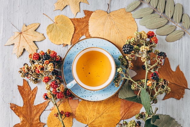 Té de calentamiento otoñal en una mesa de madera con hojas de árbol de otoño cerca