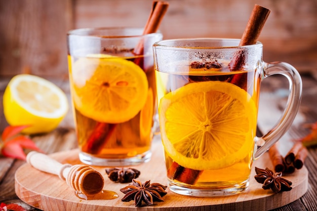 Té caliente con anís limón y canela en tazas de vidrio sobre mesa de madera