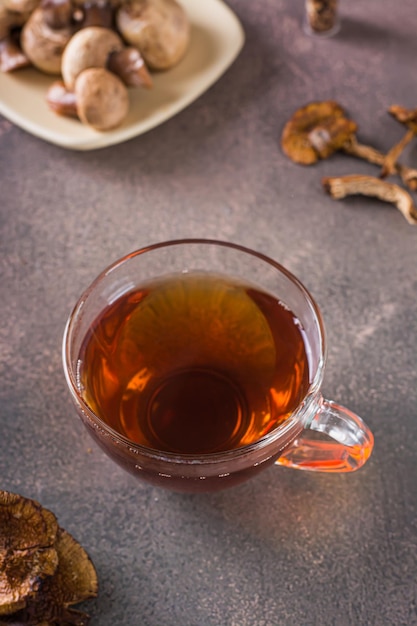 Té caliente casero de champiñones secos en una taza sobre la vista vertical de la mesa