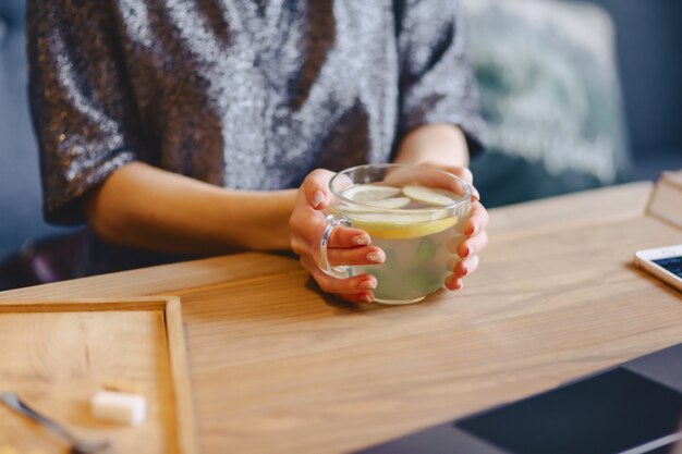 Té caliente con limón en manos delicadas de mujer.