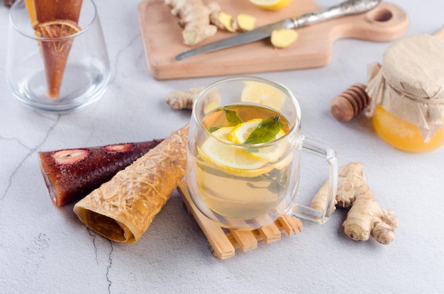 Té caliente con limón y menta en vaso de vidrio con pastilla de frutos secos