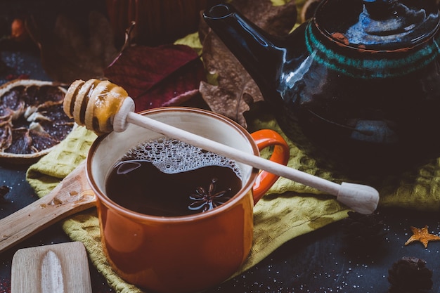 Té caliente con miel y canela en una taza de naranja atmósfera otoñal sobre una superficie oscura