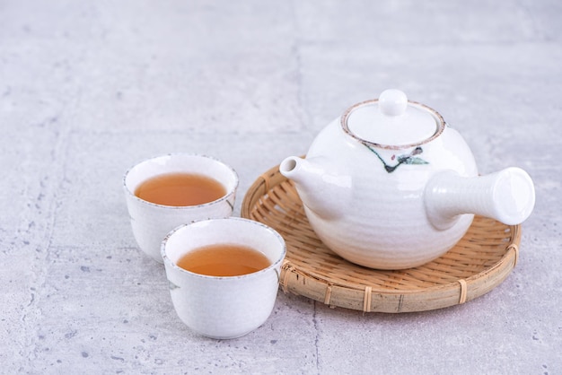 Foto té caliente en tetera blanca y tazas en un colador sobre fondo de cemento gris brillante concepto de diseño de espacio de copia de primer plano