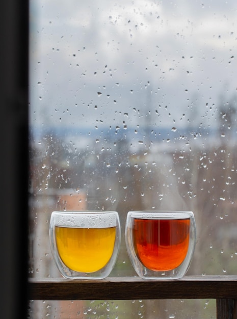 Té caliente en vidrio termo en la ventana de fondo con gotas de lluvia