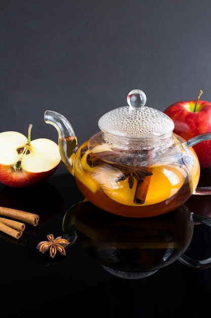 Té con canela de manzana y anís en la tetera de cristal sobre el fondo oscuro Primer plano