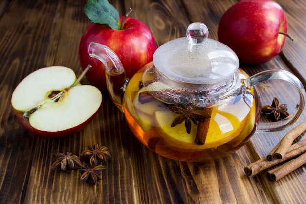 Té con canela de manzana y anís en la tetera de vidrio sobre el fondo de madera Primer plano