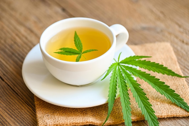 Té de cannabis a base de hierbas en una taza de té con hojas de cannabis hojas de marihuana té de salud de hierbas con plantas de hojas de cáñamo THC CBD hierbas alimentos y medicamentos