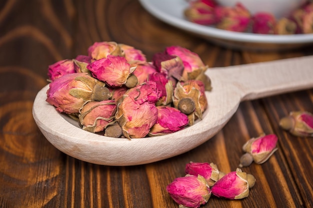 Té de capullos secos de rosas en una cuchara de madera