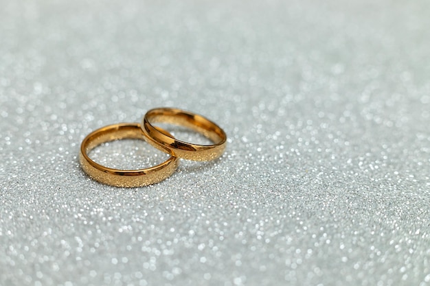 ¿Te casarías conmigo con dos anillos de boda dorados sobre un fondo de brillo plateado? Propuesta de matrimonio de compromiso