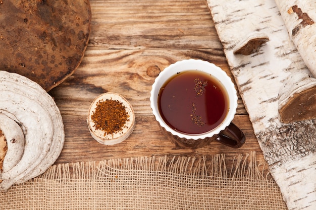 Té Chaga en una taza sobre la mesa de madera. Estilo rústico.