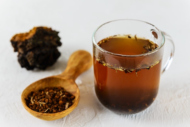 Té chaga en una taza de vidrio sobre un fondo claro