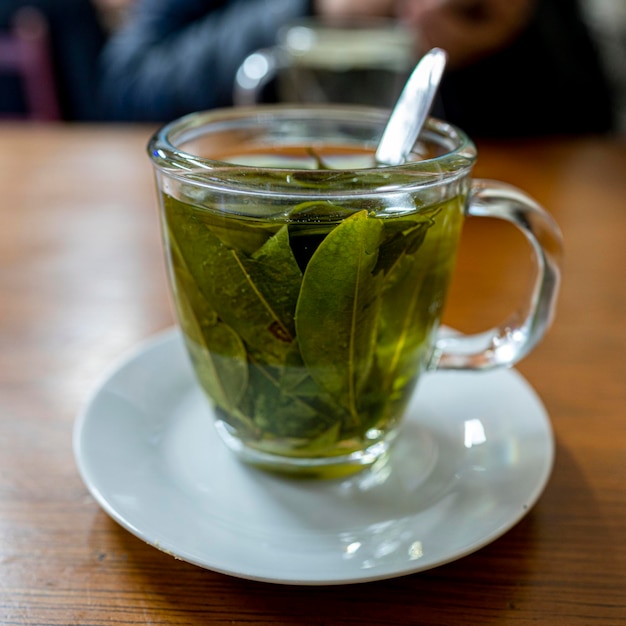 Foto té de coca en un vaso de vidrio sobre una mesa de madera