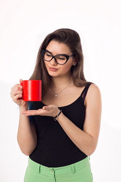 Té de consumición hermoso del café de la mujer de negocios de una taza roja.