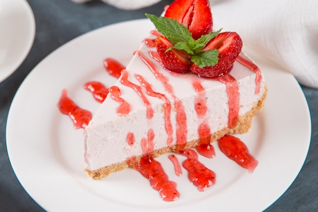 Té de desayuno dulce y delicioso pastel de queso con fresas frescas y receta casera de menta sin hornear en una mesa de piedra azul oscuro Espacio para copiar