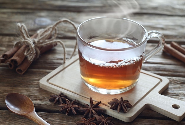 Té con especias en una taza transparente sobre una mesa de madera Las especias se encuentran cerca de canela y anís anís estrellado