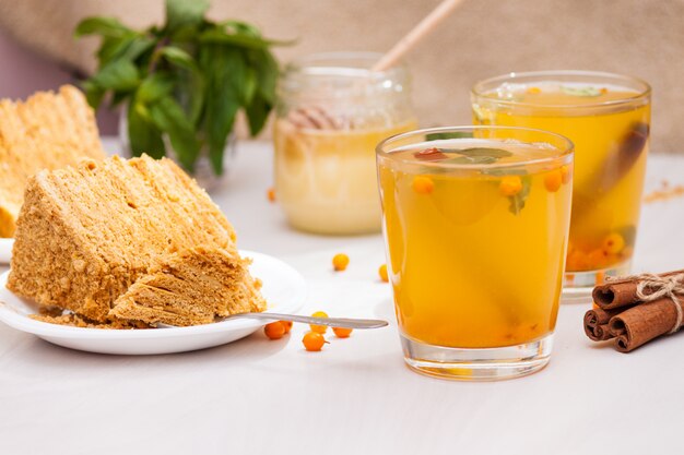 Té con espino amarillo, menta, miel, canela, pastel de miel en capas medovik.