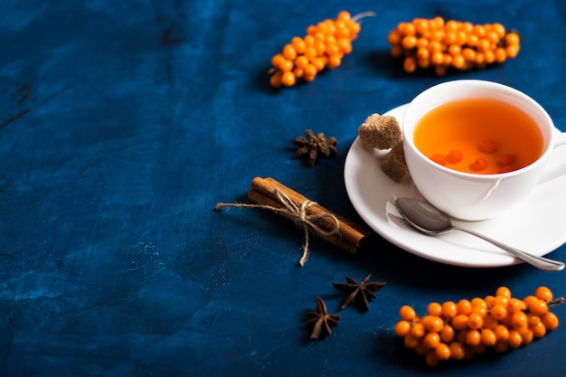 Té con espino amarillo en una superficie oscura