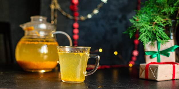 Té de espino amarillo en una tetera y una taza sobre la mesa