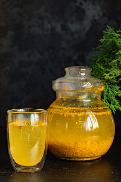 Té de espino amarillo en una tetera y en una taza transparente sobre la mesa