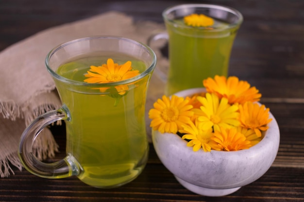 Té de flores de caléndula sobre un fondo de madera oscura.