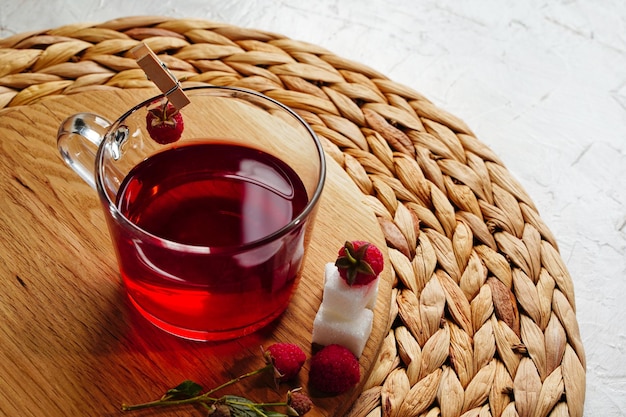 Té de frambuesa caliente en taza transparente Bayas frescas cubos de azúcar Foto de alta calidad