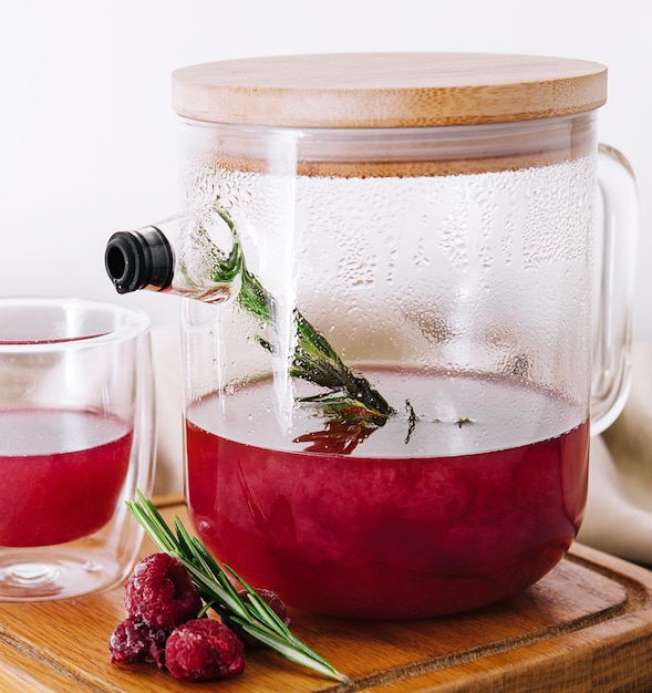 Té de frambuesa de frutas en tetera y taza de vidrio