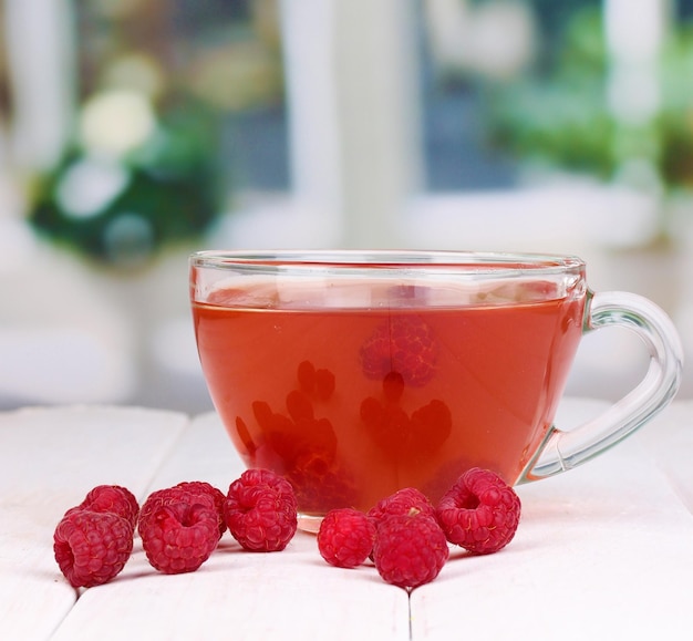 Té con frambuesas en la mesa sobre fondo brillante