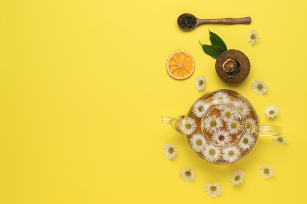 Té de frutas florales y accesorios sobre un fondo amarillo. Endecha plana. Lugar para el texto.