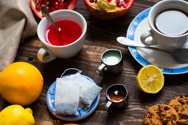 Foto té de frutas con limón, leche, miel, naranja, granada, sobre una superficie de madera