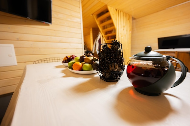 Té de frutas en una tetera en una acogedora cabaña de madera Contras en un florero Vida en el campo