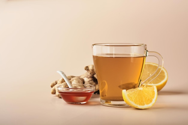 Te de gengibre. Taza de té de jengibre con limón, miel y menta sobre fondo beige. Concepto de medicina alternativa, remedio casero natural para el resfriado y la gripe. Vista superior. Espacio libre para su texto.