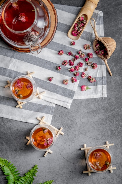 Té hecho de pétalos de rosa de té en vasos y un frasco