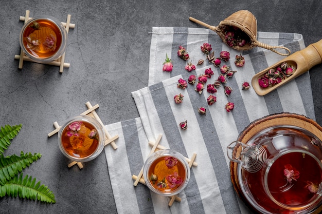 Té hecho de pétalos de rosa de té en vasos y un frasco