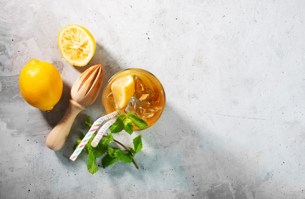 Té helado de limón sobre fondo gris concreto con menta y hielo