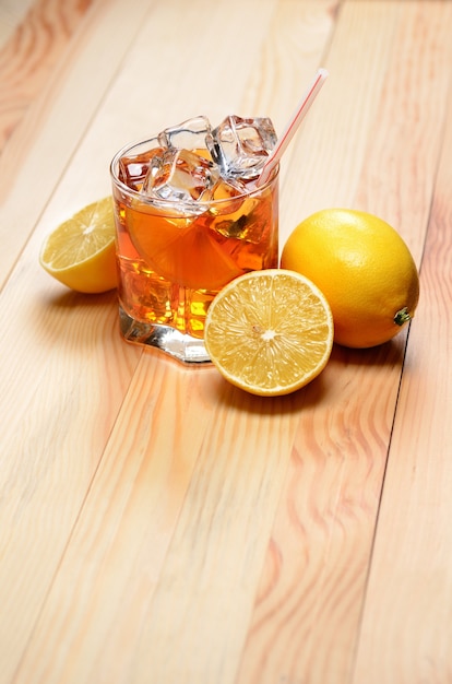 Té helado con limones en una mesa de madera